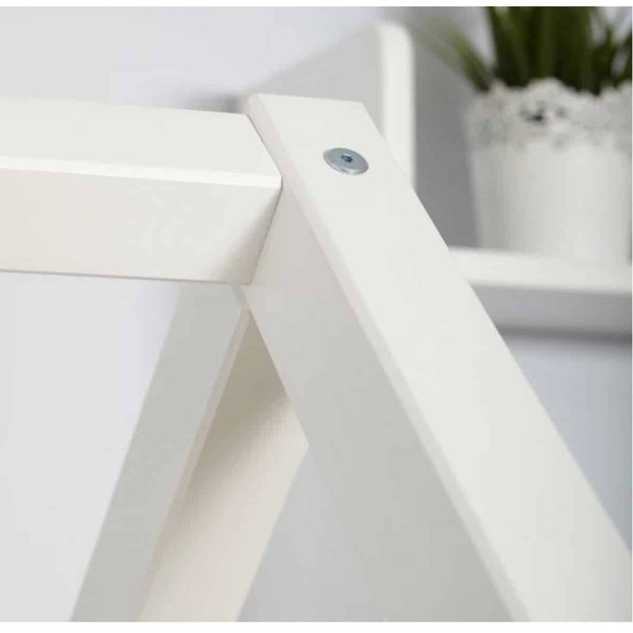 White shelf with a small plant in the background