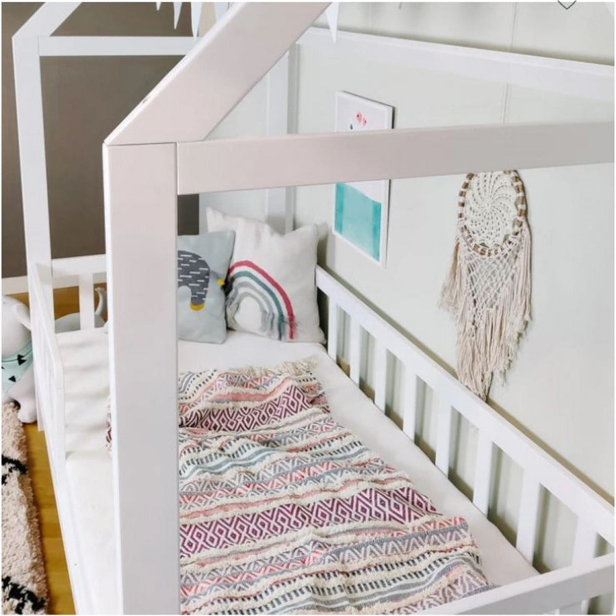 Children's room with a white crib, colorful blanket, and decorative items.