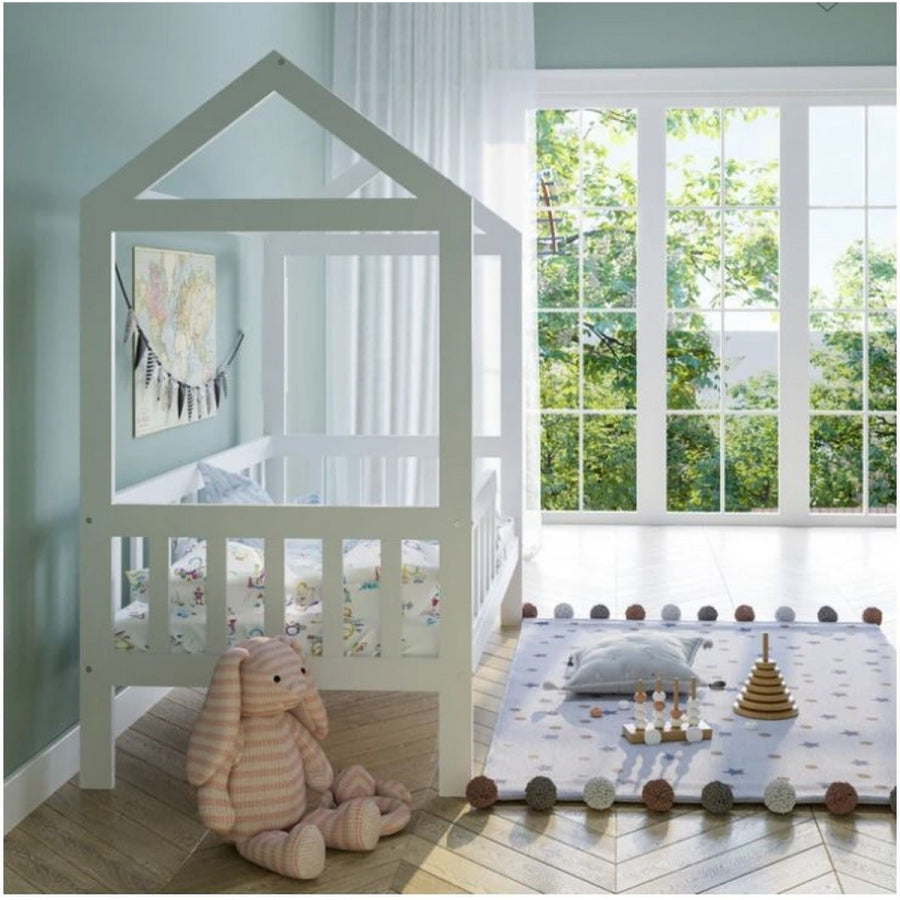 Children's room with a house-shaped crib, teddy bear, and toys on a rug.