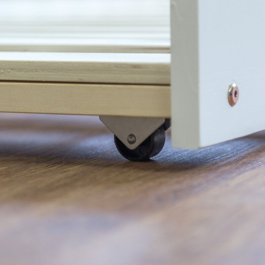 Close-up of a wooden drawer with a wheel on a wooden surface.
